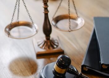 A striking image featuring a brass justice scale and gavel on a wooden desk, symbolizing law and justice.