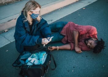 Paramedic provides first aid to injured man lying on roadside.