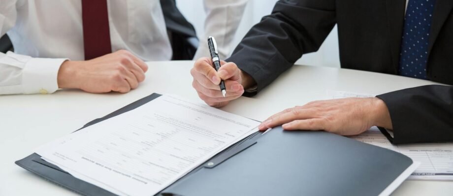 Two professionals signing a contract at a business meeting in an office.