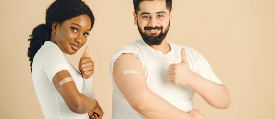 Two people showing band-aids and thumbs up after vaccination. Positive health concept.