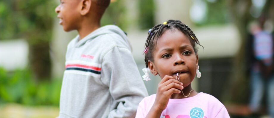 selective focus photography of girl biting her pendant beside a boy in gray pullover hoodie