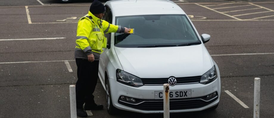 man in yellow jacket standing beside white car