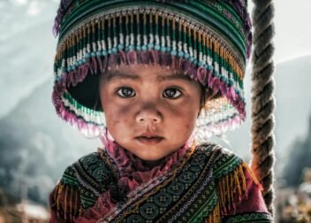 Close-up of a Vietnamese child in traditional attire with a colorful hat, highlighting cultural heritage.