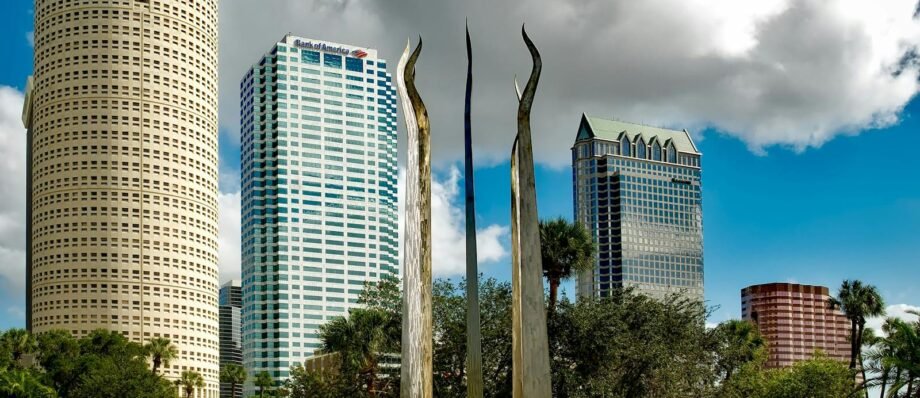 Tampa's skyline features tall skyscrapers and modern sculptures under a bright sky.