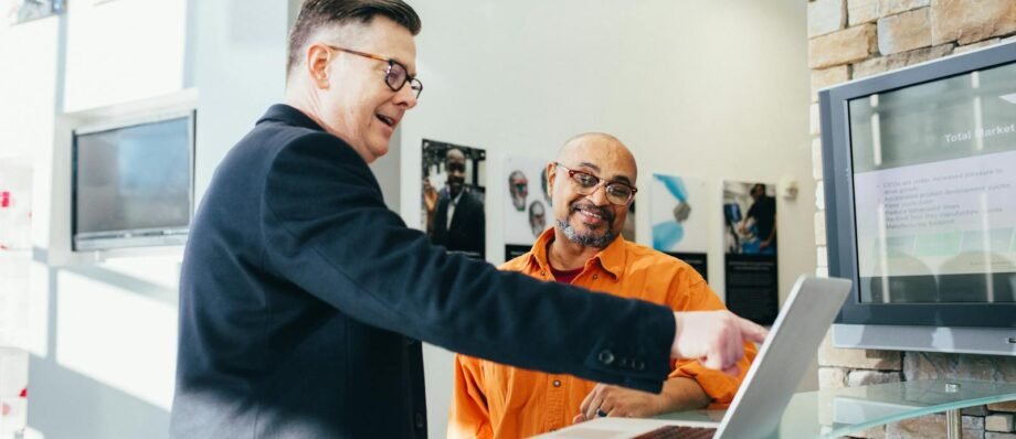 Two businessmen having a lively discussion in a modern office setting, pointing at a laptop screen.