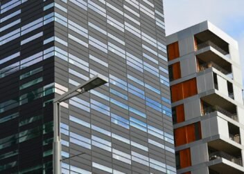 Low angle view of a modern glass office building and residential structure in daylight.