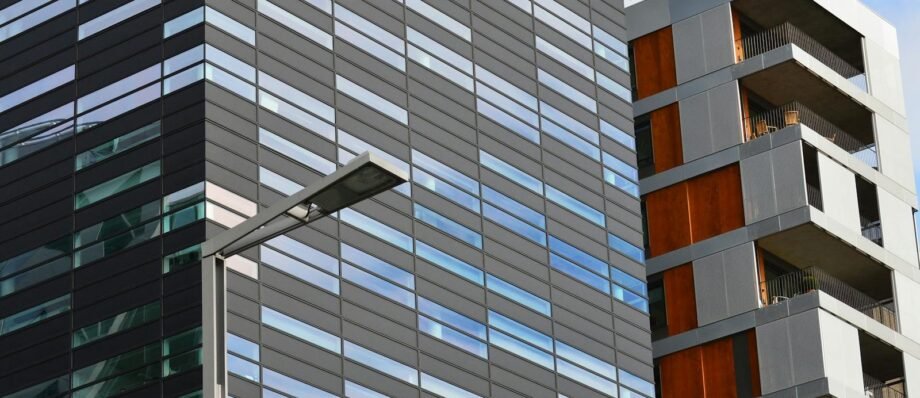 Low angle view of a modern glass office building and residential structure in daylight.