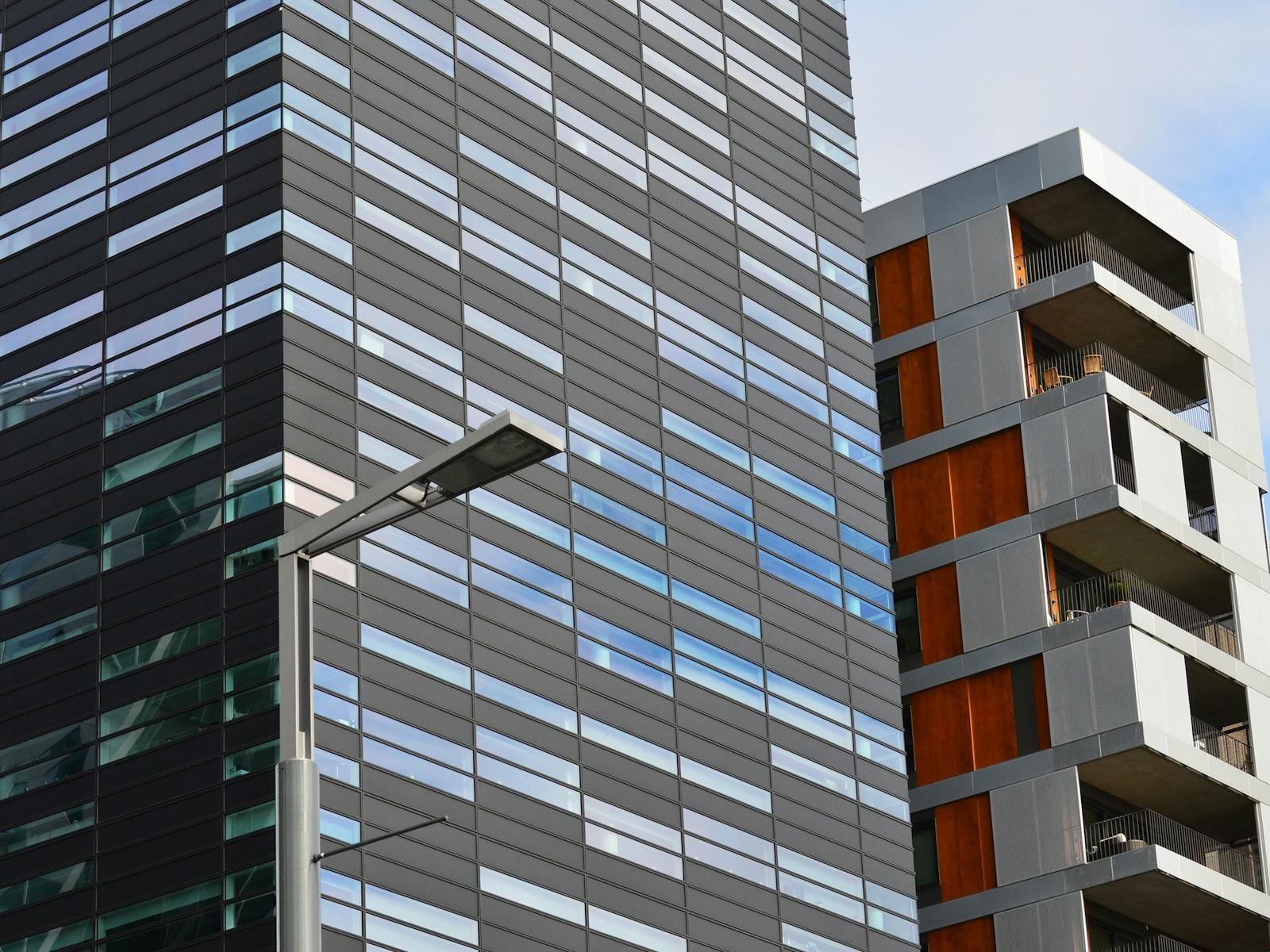 Low angle view of a modern glass office building and residential structure in daylight.