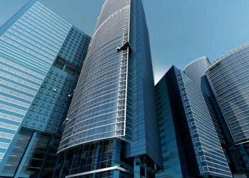 Futuristic urban skyscrapers with glass facades reflecting a vibrant blue sky.