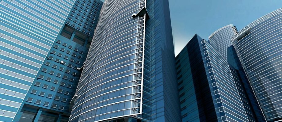 Futuristic urban skyscrapers with glass facades reflecting a vibrant blue sky.