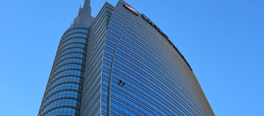 High-rise modern building in Milan under a clear blue sky, showcasing urban architecture.