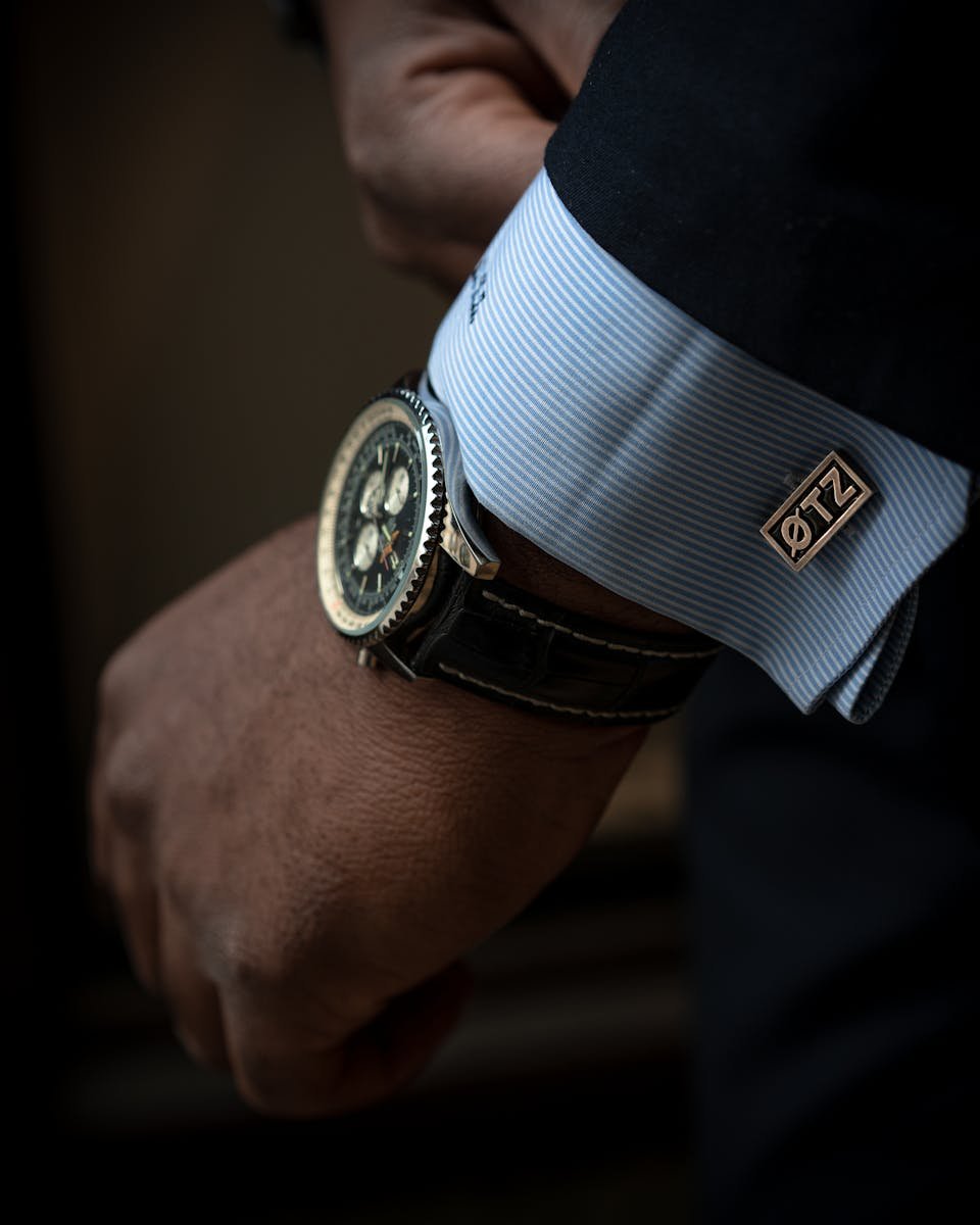 Close-up of a sophisticated black wristwatch and cufflink on a man's wrist, showcasing elegance and style.