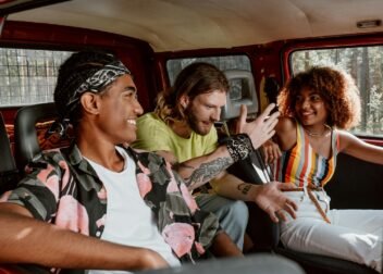 Three friends share a joyful moment inside a van during a summer road trip.