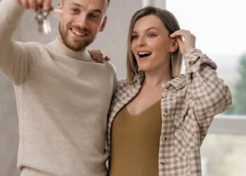 Excited couple holding keys to their new home, celebrating together indoors.
