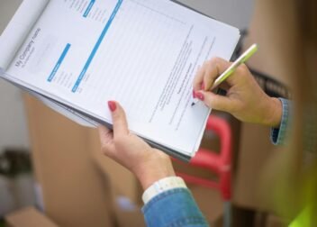 Close-up of woman's hand signing a document on a clipboard. Ideal for business and legal themes.