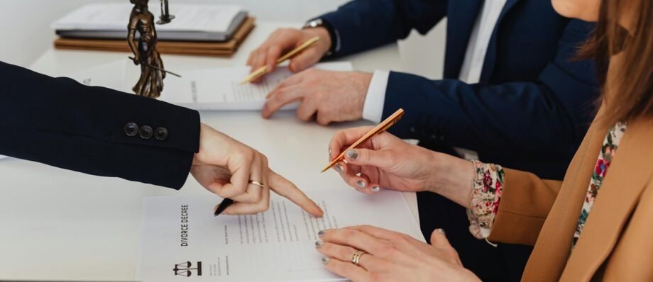 Hands signing a divorce decree, with a justice statue nearby, symbolizing legal proceedings.