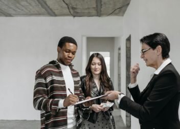 A diverse couple signing documents with a realtor in a new home setting.