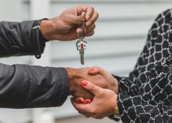 Close-up of a realtor handing over a house key to a new homeowner, symbolizing ownership and investment.