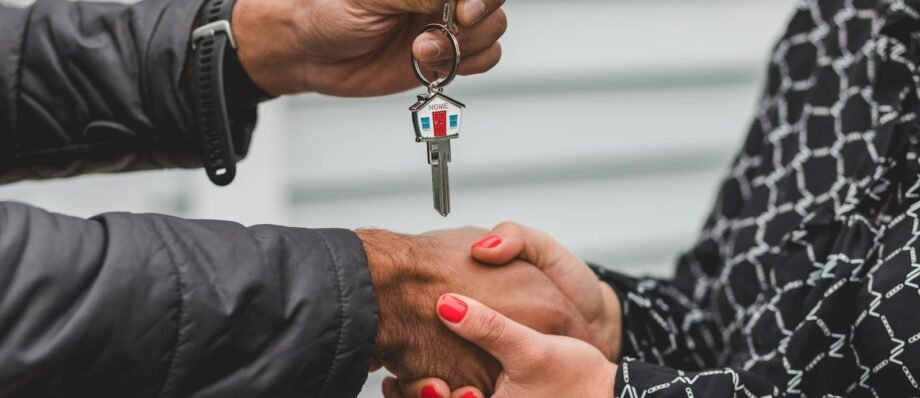 Close-up of a realtor handing over a house key to a new homeowner, symbolizing ownership and investment.