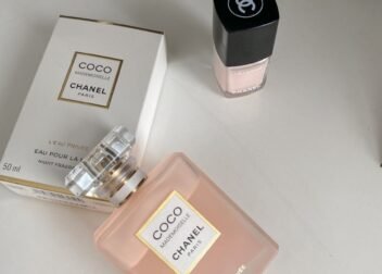 Elegant product shot of Chanel Coco Mademoiselle perfume and nail polish on a white surface.