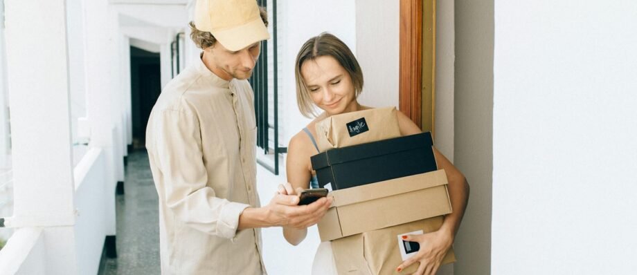 A man and woman engaged in a home delivery package exchange, smiling.